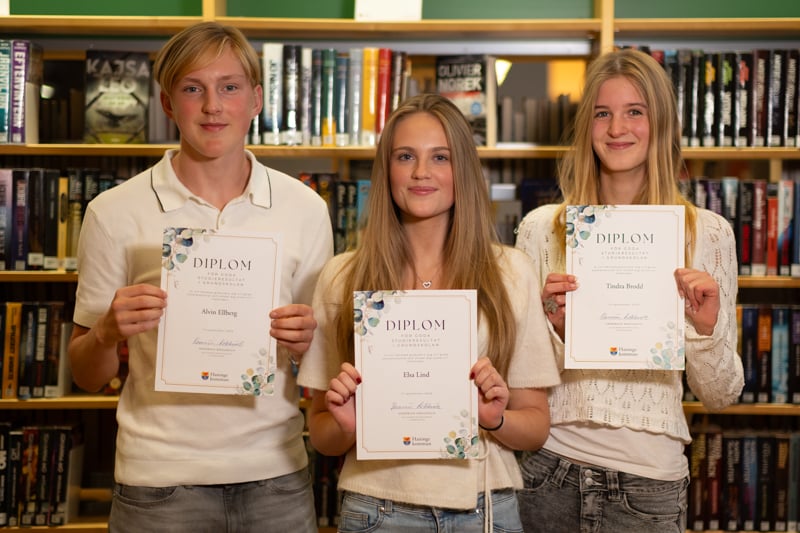 En pojke och två flickor håller varsitt diplom.
