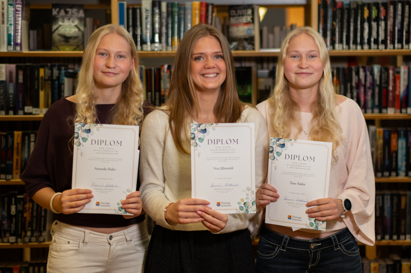 Tre flickor håller varsitt diplom.