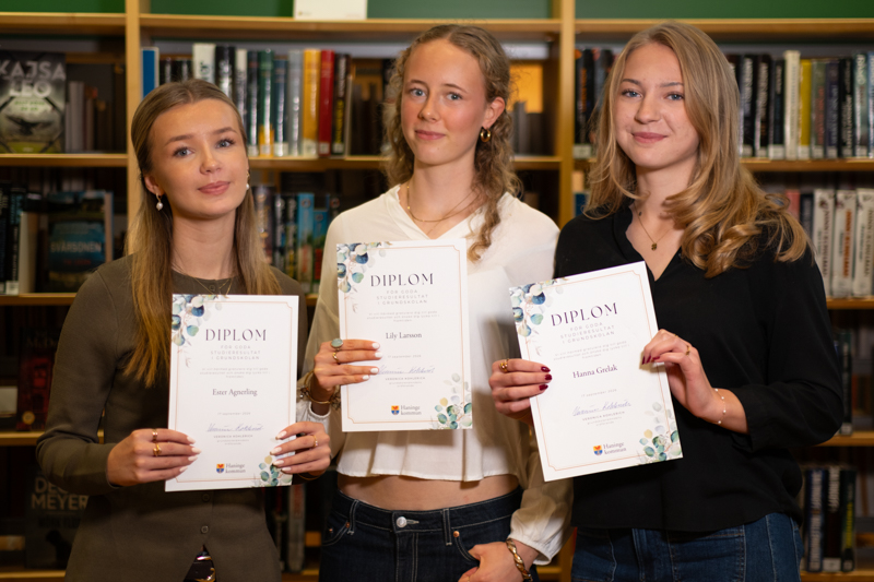 Tre flickor håller varsitt diplom