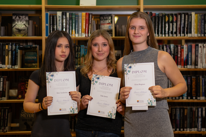 Tre flickor håller varsitt diplom