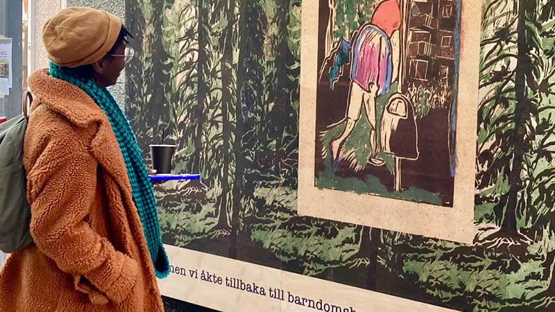 Kayo Mpoyi framför konstverket Ett rådslag i skogen. Konstnären Kayo Mpoyi står framför konstverket Ett rådslag i skogen