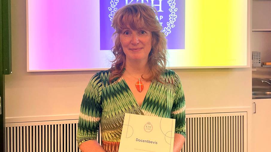 Eva Hartell har fått docentbevis. Eva håller i ett diplom med texten "Docentbevis"