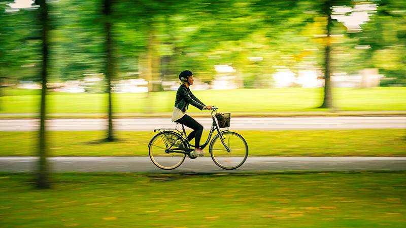 Cyklist som cyklar längst med en färgsprakande gräsmatta.