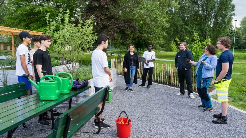 Ungdomar samlade i Höglundaparkens köksträdgård tillsammans med handledare som ger instruktioner
