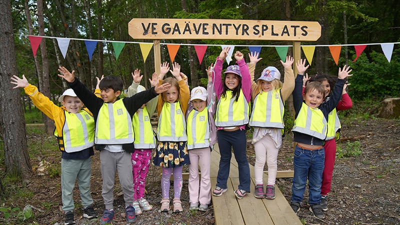 Flera barn framför en skylt med texten "Vega äventyrsplats"