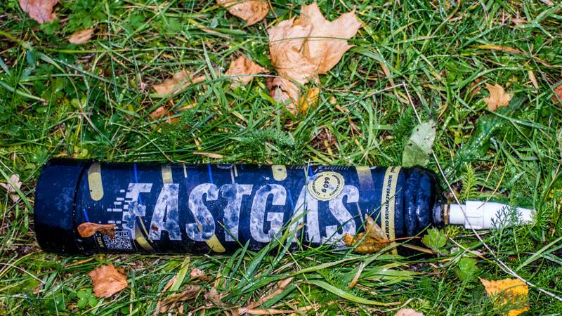 Lustgas En lustgastub ligger slängd bland gräs och löv.