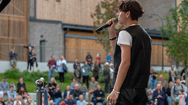 En pojke i tonåren sjunger på scen.