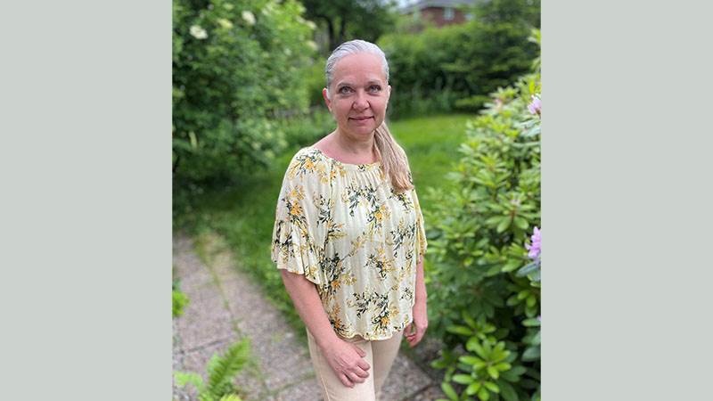 En kvinna står utomhus och tittar mot kameran
