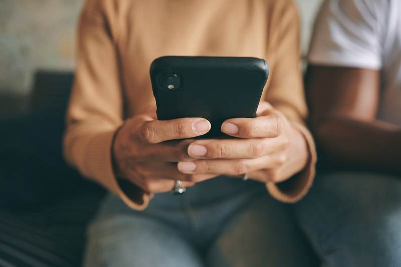 Kvinna som knappar in ett telefonnummer i telefonen