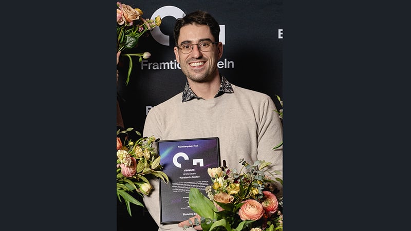 Glad man med diplom och blommor.