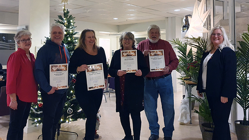 Glada människor på rad visar upp diplom