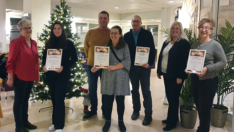 Glada människor på rad visar upp diplom