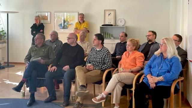En grupp människor sitter på stolar och lyssnar på en presentation