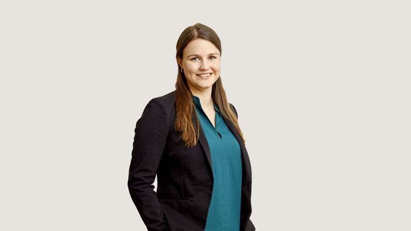 En kvinna står mot en grå bakgrund