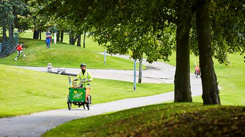 Person cyklar på lådcykel efter cykelväg i Eskilsparken
