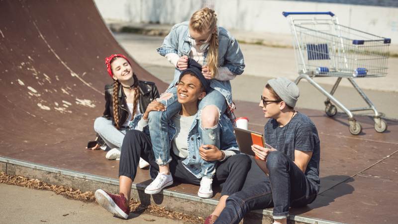Fyra glada tonåringar sittandes i skateboardramp.