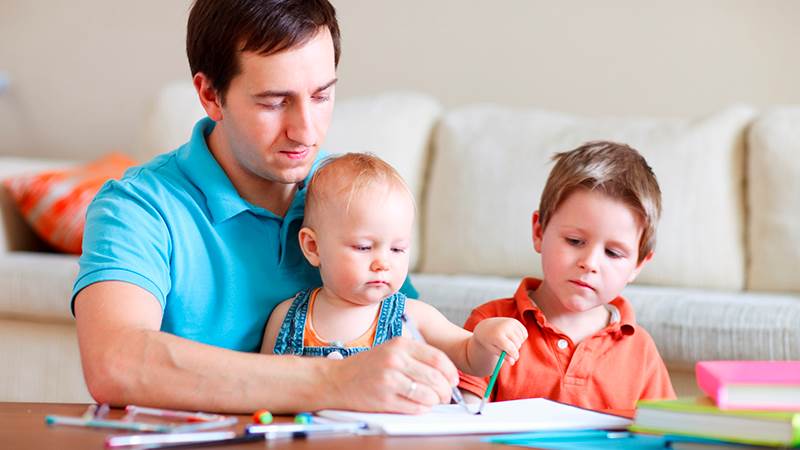 En pappa ritar tillsammans med  två barn.