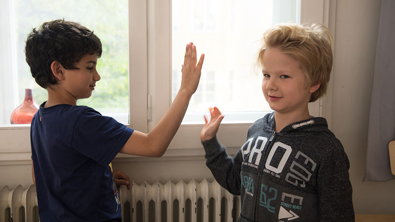 Två pojkar gör high five med varandra i ett klassrum
