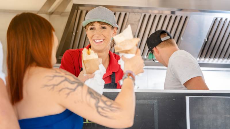 Kvinna får mat från en annan kvinna i en food truck