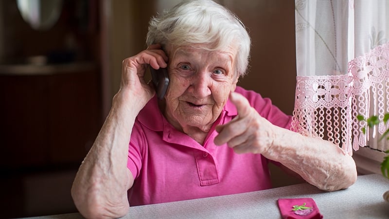 En äldre kvinna sitter vi ett bort och pratar i telefon