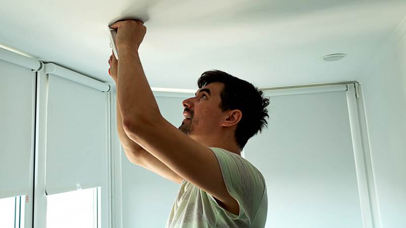 En man skruvar upp en lampa i taket