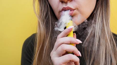 En ung kvinna röker e-cigarett.