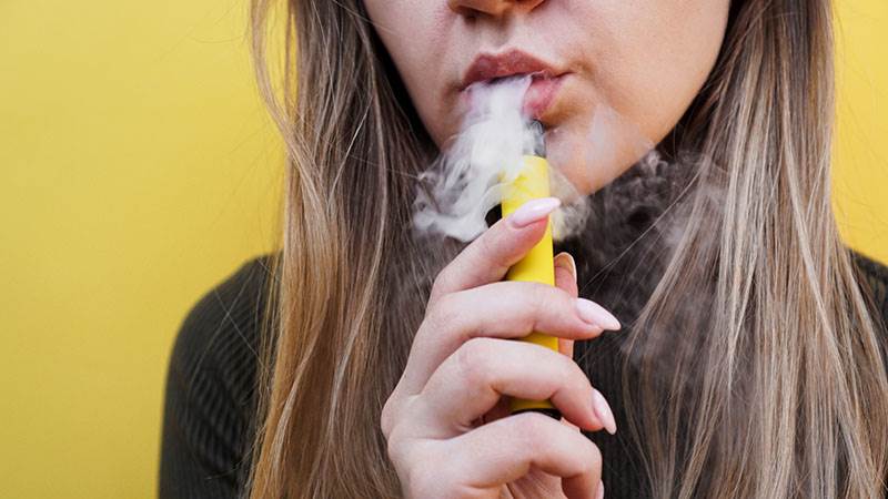 En ung kvinna röker e-cigarett.