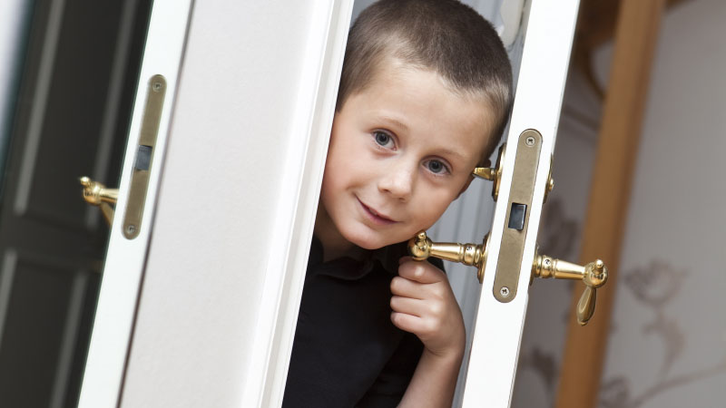 En pojke kikar ut genom en dörröppning