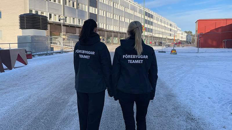Kommunens förebyggarteam är en del av arbetet med att nå utsatta personer tidigare. Två personer står med ryggen mot kameran och har på sig svarta jackor med texten "Förebyggarteamet"