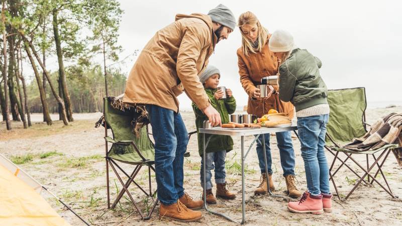 Familj har picknick på stranden på hösten.