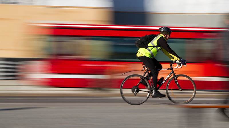Cyklist i trafiken med en buss i bakgrunden