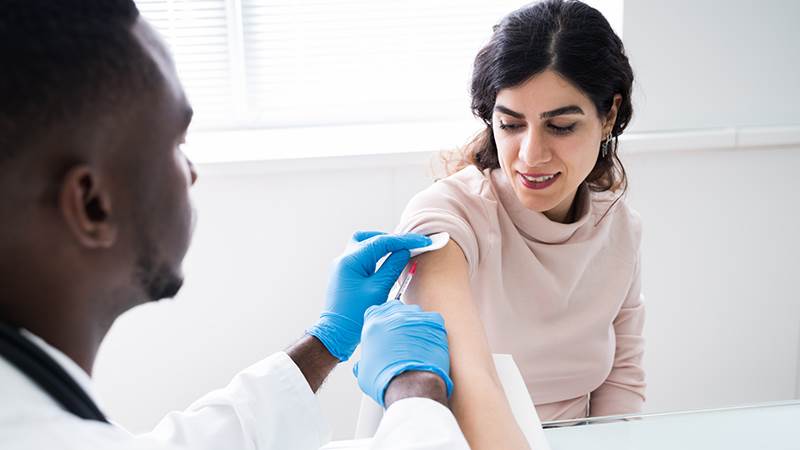 En kvinna får vaccin av en manlig läkare