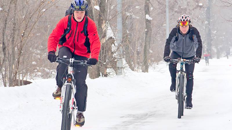 Två vintercyklister på snöig väg