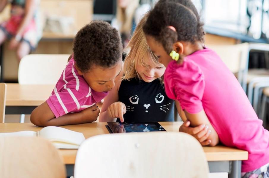 Tre barn som sitter runt en padda i ett klassrum
