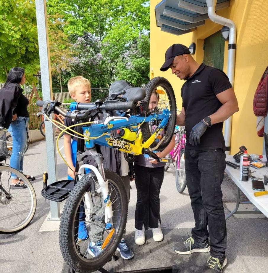 Eleverna på Nakterhusskolan servar sina cyklar med hjälp av cykelreparatören Latif Bazzine. Cykelreparatör Latif Bazzine och två barn servar en cykel.