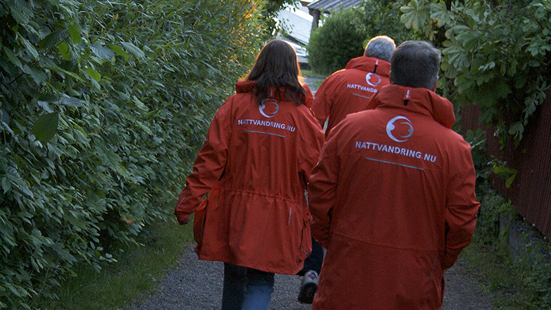 Tre personer går utomhus. Alla har röda jackor med texten Nattvandrare.nu
