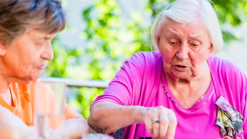 Två äldre damer sitter vid ett bord utomhus