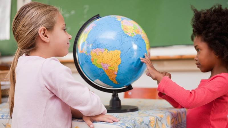 Skolplikten i Sverige gäller från förskoleklass hela vägen upp till nian. Två skolelever tittar på en jordglob.