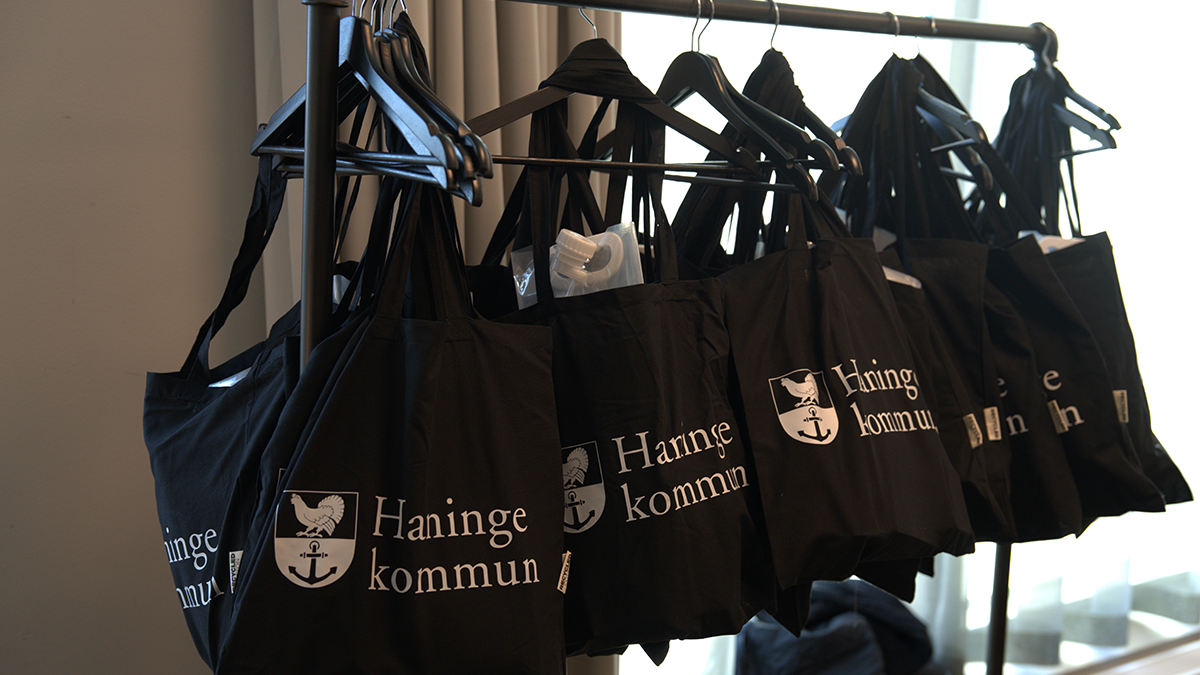 En hängare med svarta tygpåsar med Haningeloggan på.
