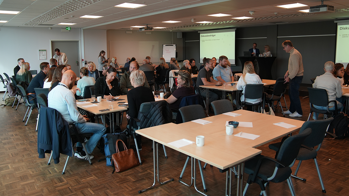 En grupp diskuterar i konferenssal.