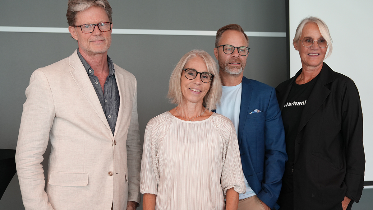 Två män och två kvinnor på rad i konferenslokal.