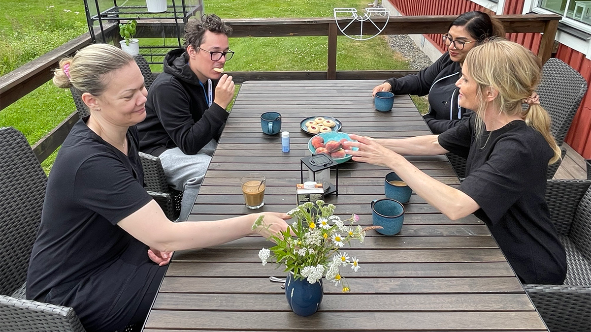 Fyra personer sitter omkring ett bord på en altan.