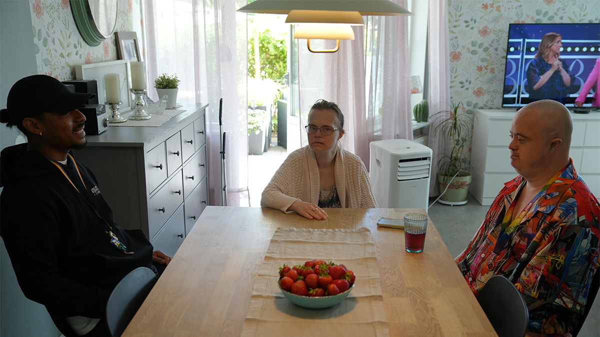 Tre personer samtalar vid ett bord. 
