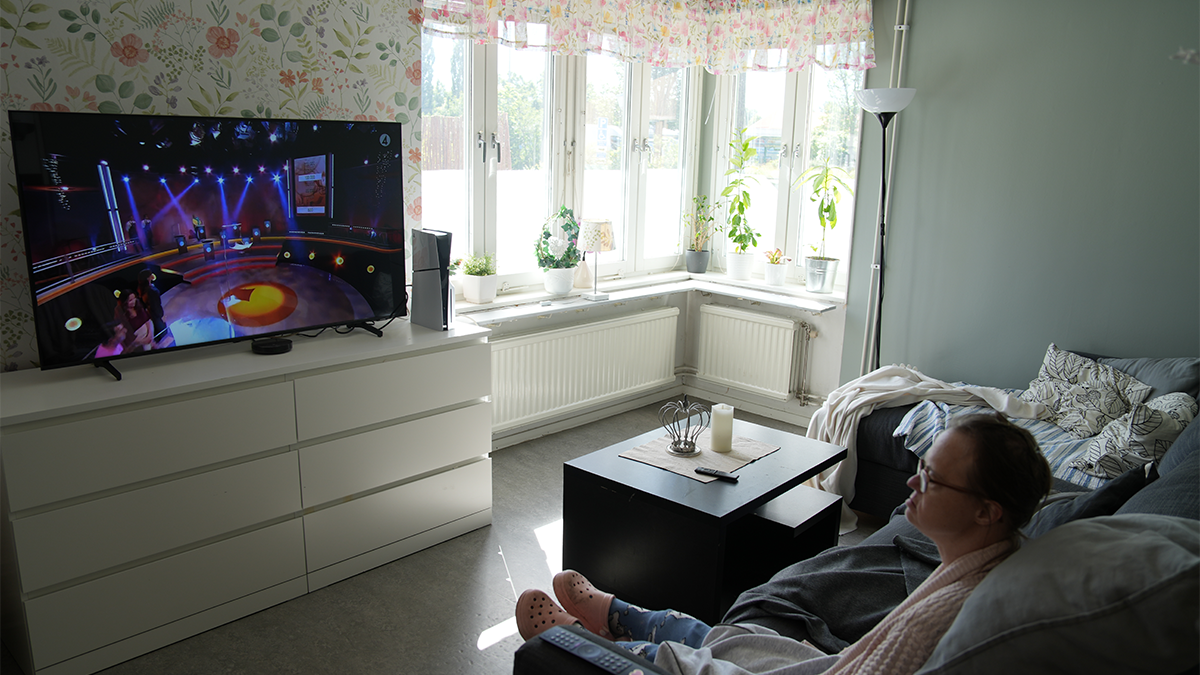 En kvinna ligger i soffan och tittar på film. 