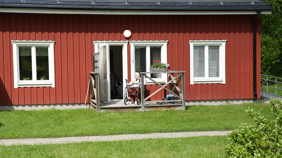 En kvinna på en altan utanför ett rött hus.