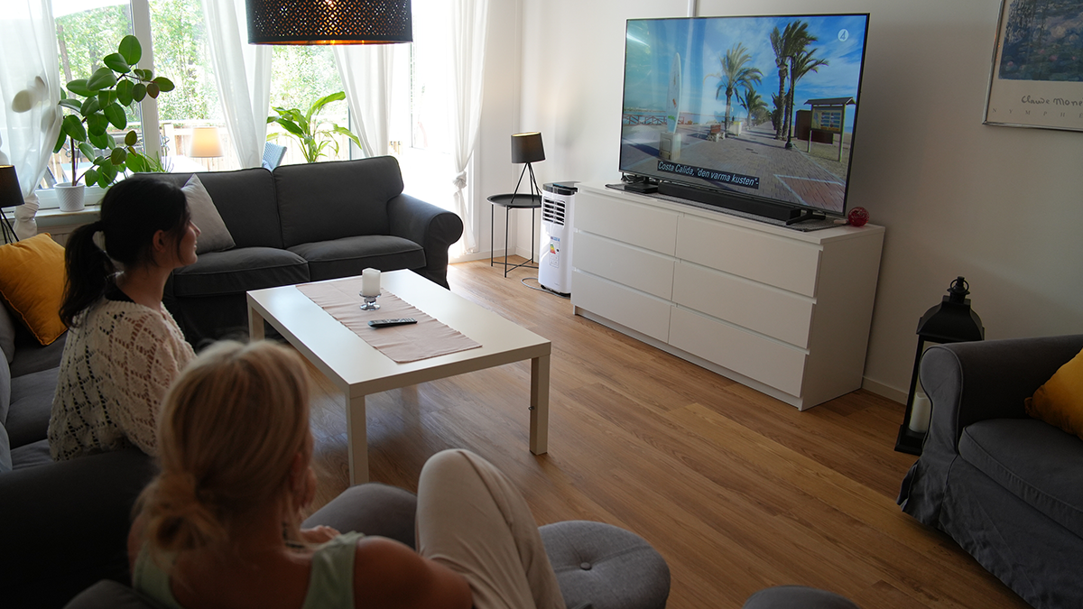 Två kvinnor tittar på tv i en soffa. 
