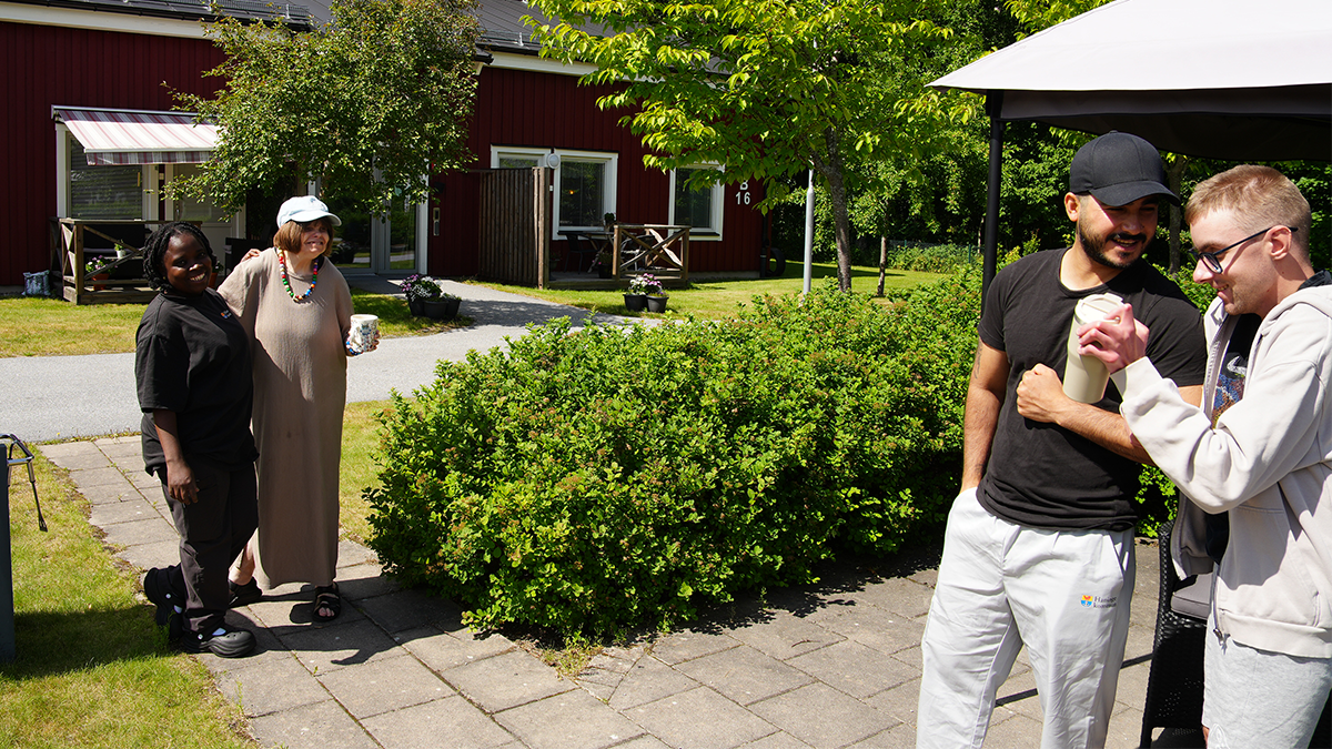 Fyra personer pratar i en trädgård.