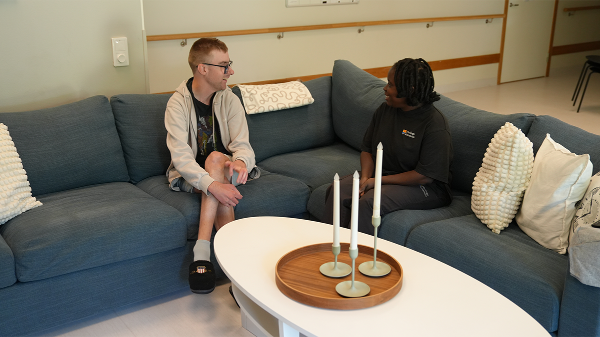 Två personer pratar i en soffa. 