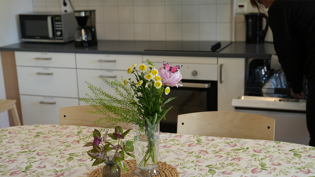 En kvinna plockar ur en diskmaskin bakom en bukett blommor.
