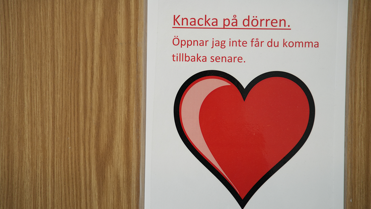 En skylt där man ombeds knacka med ett rött hjärta på.